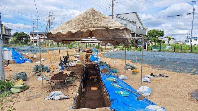 Archaeological excavation trenches and protective tents at the Shinpukuji Shell Mound in Saitama, Japan.