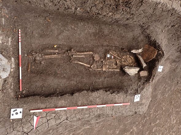 Excavated Roman child's grave with stone remains and archaeological measuring scales at Augusta Traiana in Stara Zagora, Bulgaria.