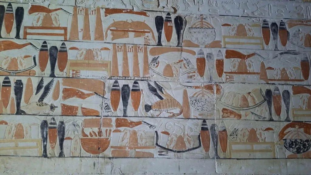 Ancient Egyptian funerary paintings showing food offerings, vessels, and other goods on the decorated walls of Weni's tomb.