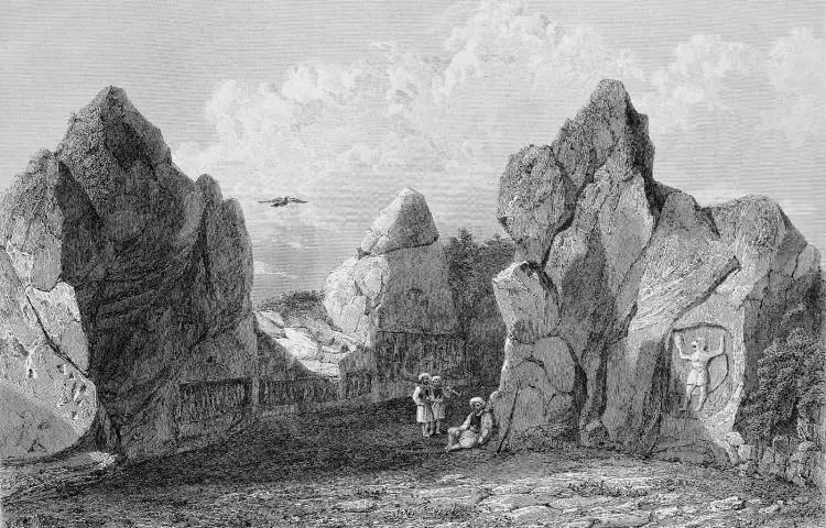  Historical black-and-white engraving of the Yazılıkaya rock sanctuary near Hattusa, depicting carved Hittite figures on the rock walls and visitors among the towering stone formations.