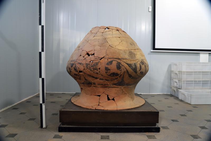 Large reconstructed Neolithic pottery vessel with dark spiral decorations from the Nanzuo archaeological site.