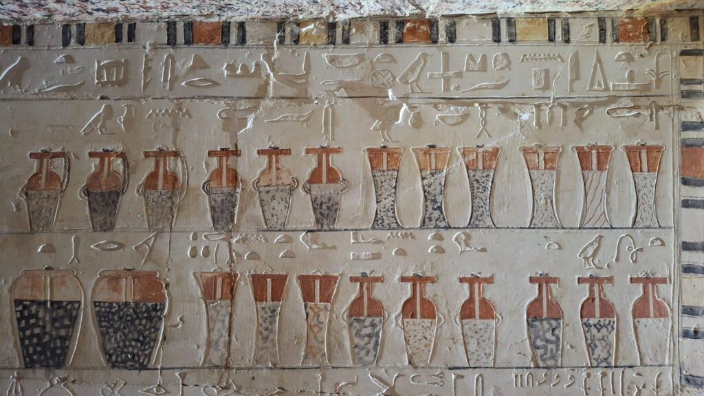 Colorful ancient Egyptian vessel paintings and hieroglyphs preserved on the walls of Weni's burial chamber at Saqqara.