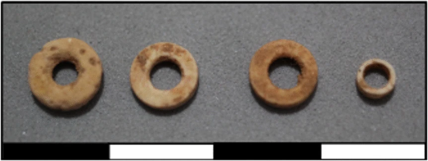 Four prehistoric circular beads made from ostrich eggshell, recovered from a 4,400-year-old burial in Western Sahara.