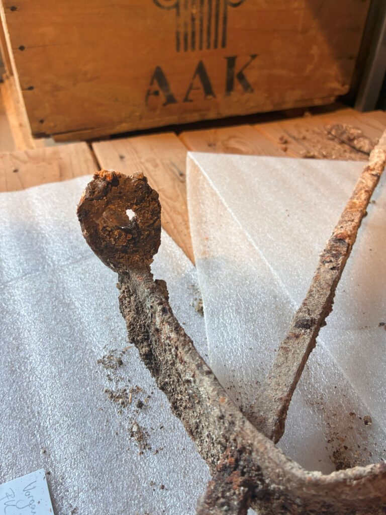 
Close-up of a heavily corroded iron eyelet attached to an ancient Roman window grille, showing a possible fastening point for the window frame.