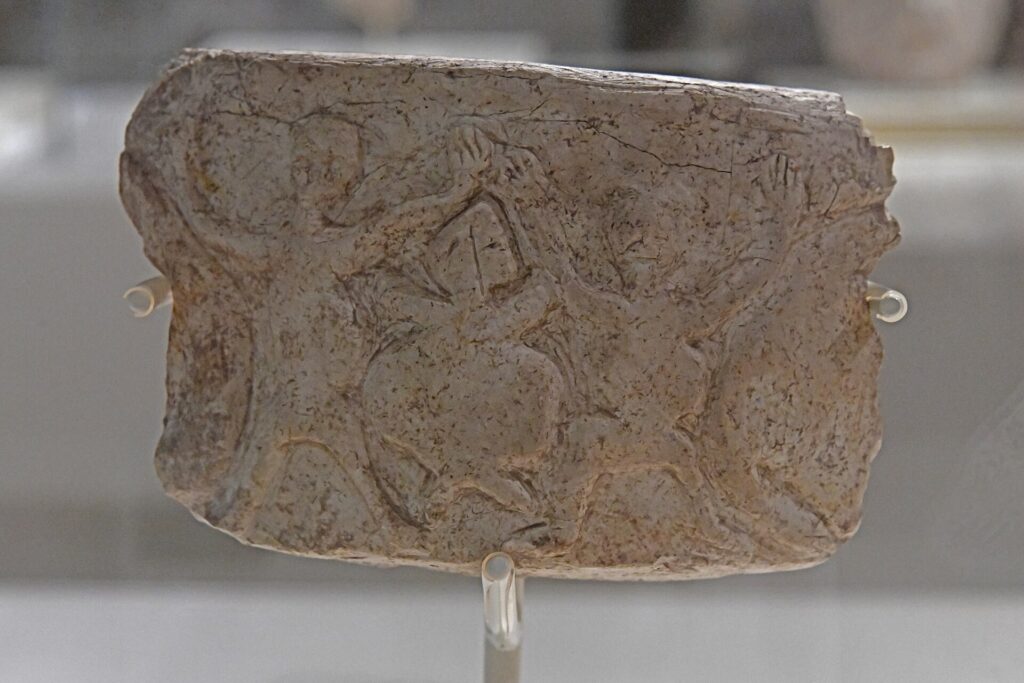 Ancient limestone bowl fragment from Nevalı Çori showing three carved figures interpreted as a possible prehistoric dance scene.